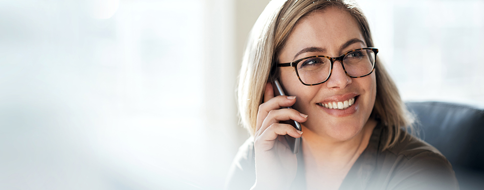 woman with blonde hair and glasses on the phone