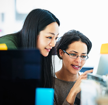 two woman in an office looking at a computer screen