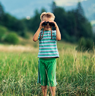 boy with binoculars in grass field
