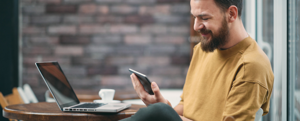 Man with beard wearing a mustard colour shirt sitting and staring at an iPad